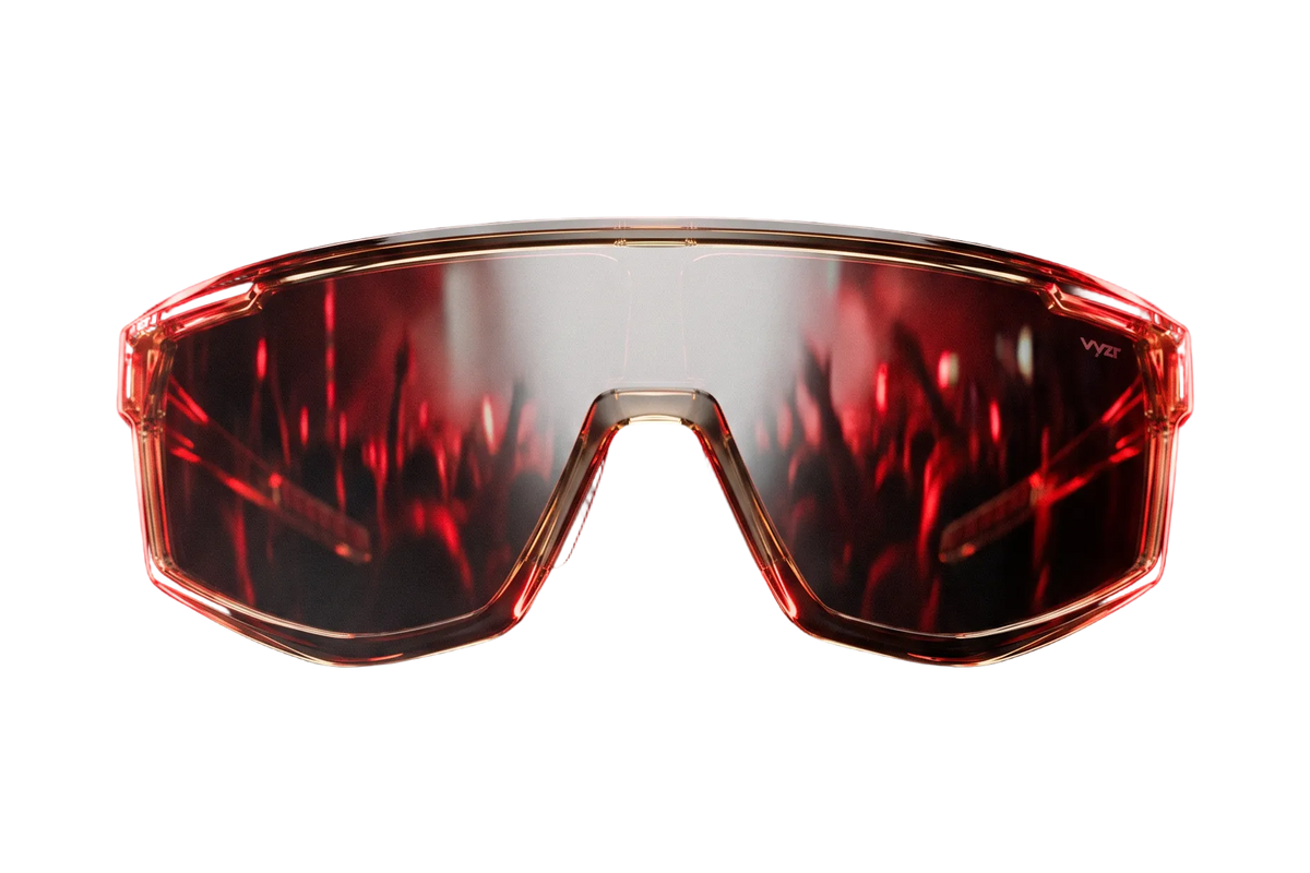 A pair of futuristic shield-style vyzr sunglasses with a translucent red frame and red-tinted lenses, shown against a dark smoky background.